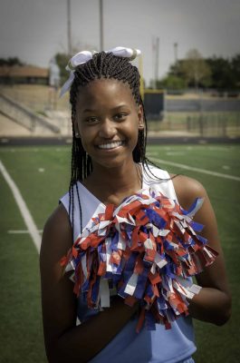 High school female cheerleader posing with her pom pom.